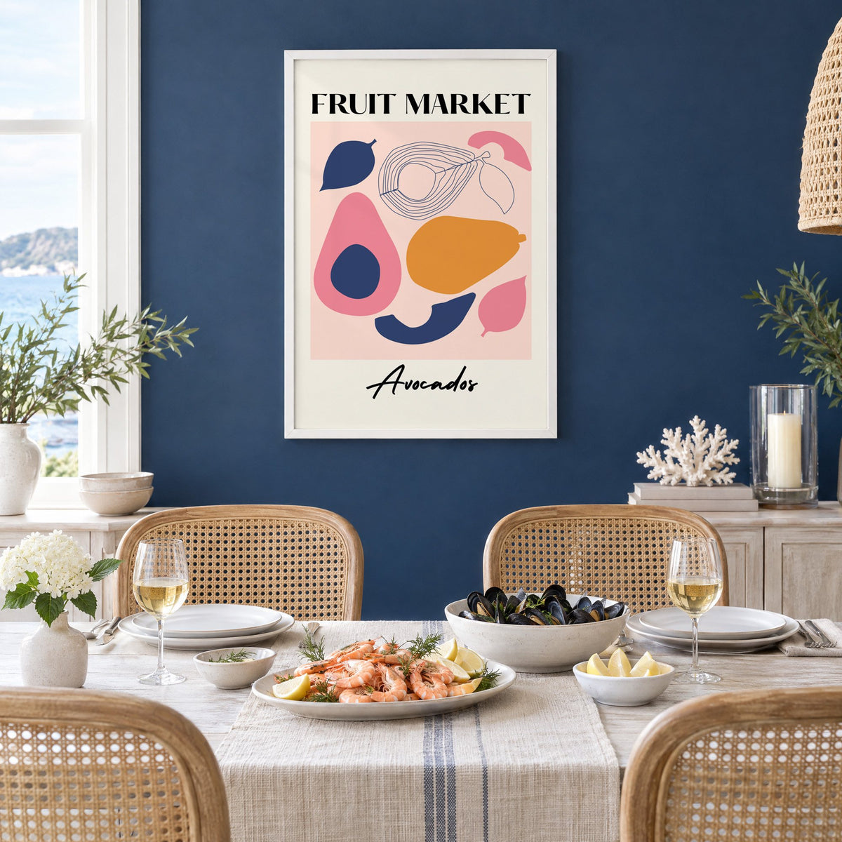 FRUIT MARKET Avocados cut-paper print in a white frame on a navy wall above a dining table set with shrimp and mussels
