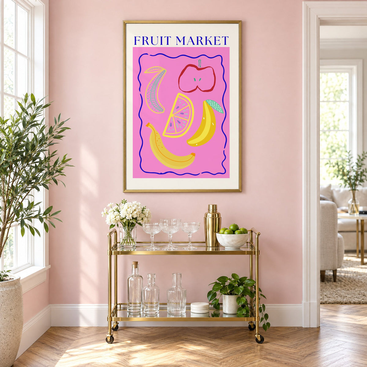 FRUIT MARKET bananas, apple and citrus print in a brass frame on a blush pink wall above a gold bar cart with glassware