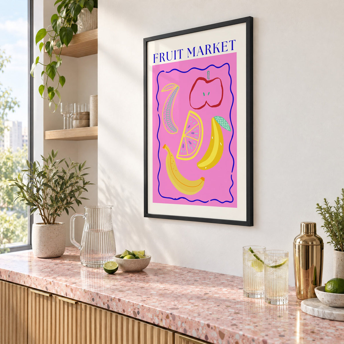 FRUIT MARKET bananas, apple and citrus print in a black frame above a pink terrazzo cocktail counter with limes, seen at an angle