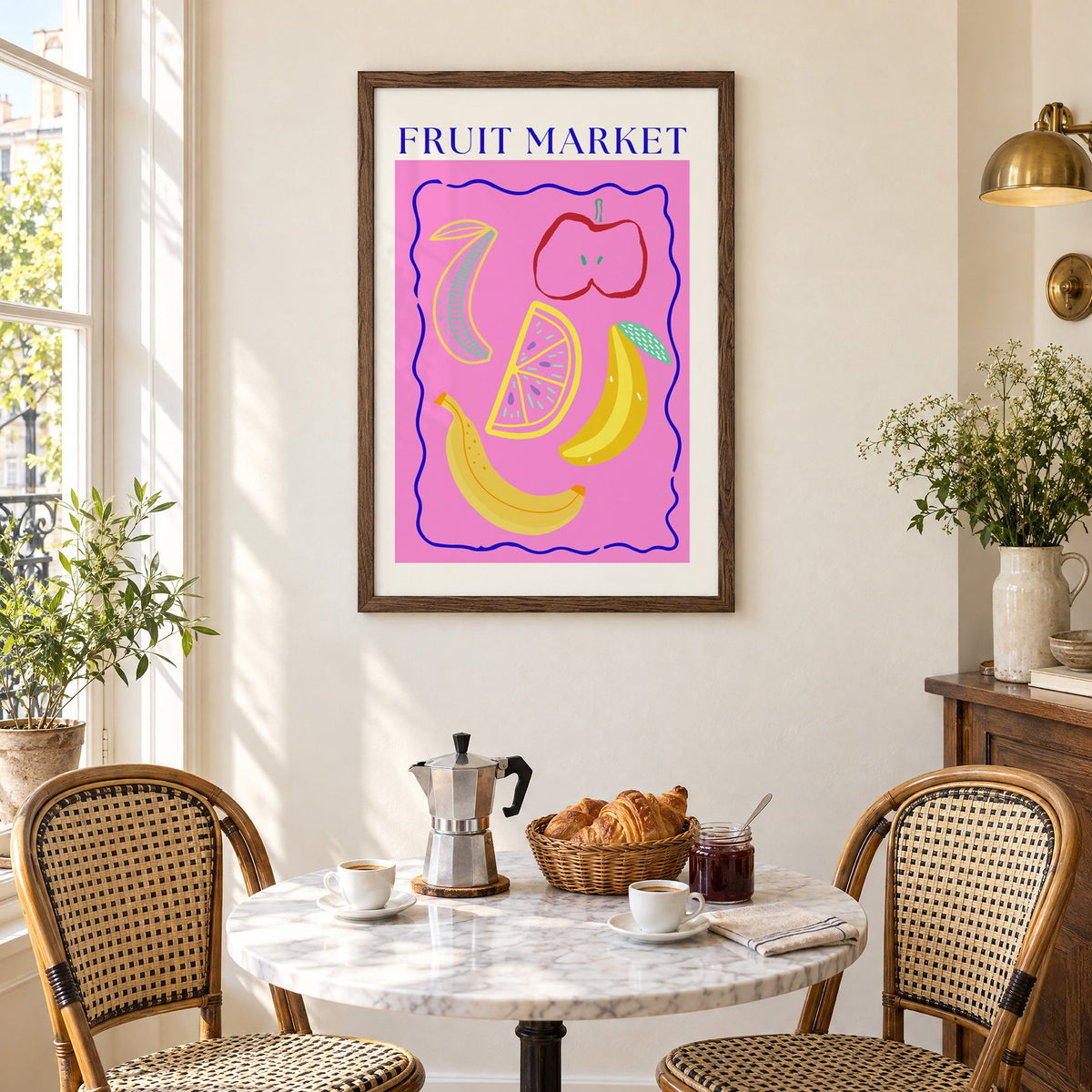 FRUIT MARKET bananas, apple and citrus print in a walnut frame above a marble bistro table with croissants and rattan chairs