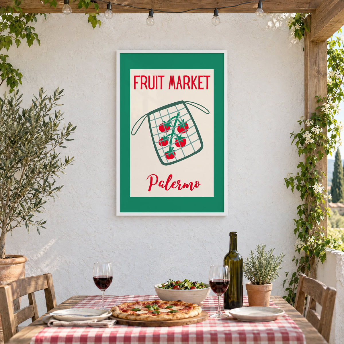 FRUIT MARKET Palermo tomato net bag print in a white frame on a stucco wall above a checked-cloth table with pizza and red wine