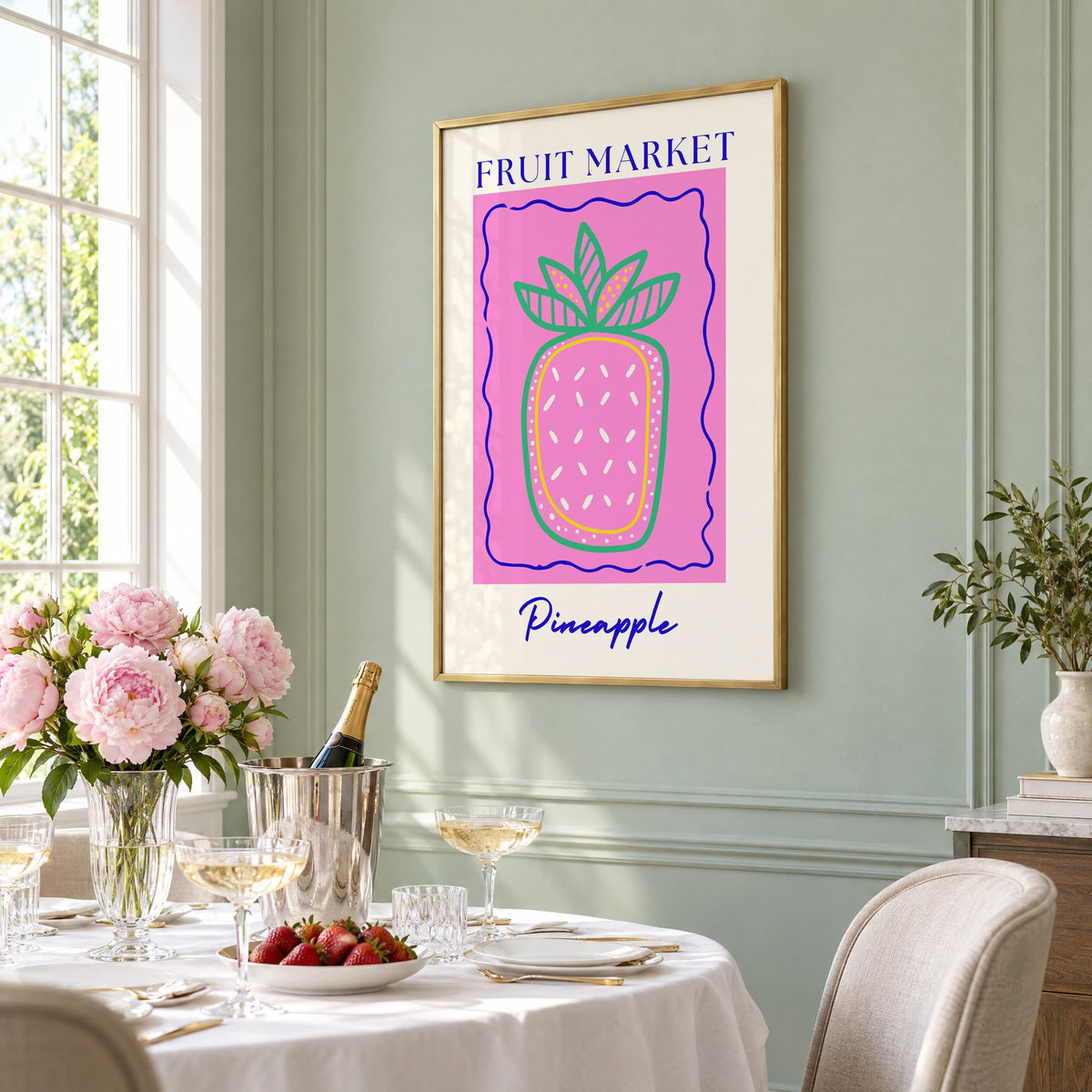 FRUIT MARKET Pineapple pink wavy frame print in a brass frame on a sage wall above a brunch table with champagne and peonies, seen at an angle