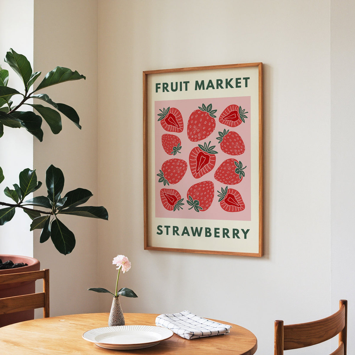 Fruit Market strawberry print in a walnut frame above a round table beside a fiddle-leaf fig