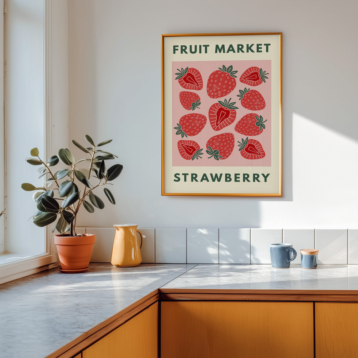 Fruit Market strawberry print shown in a gold frame above a marble counter in a tan kitchen
