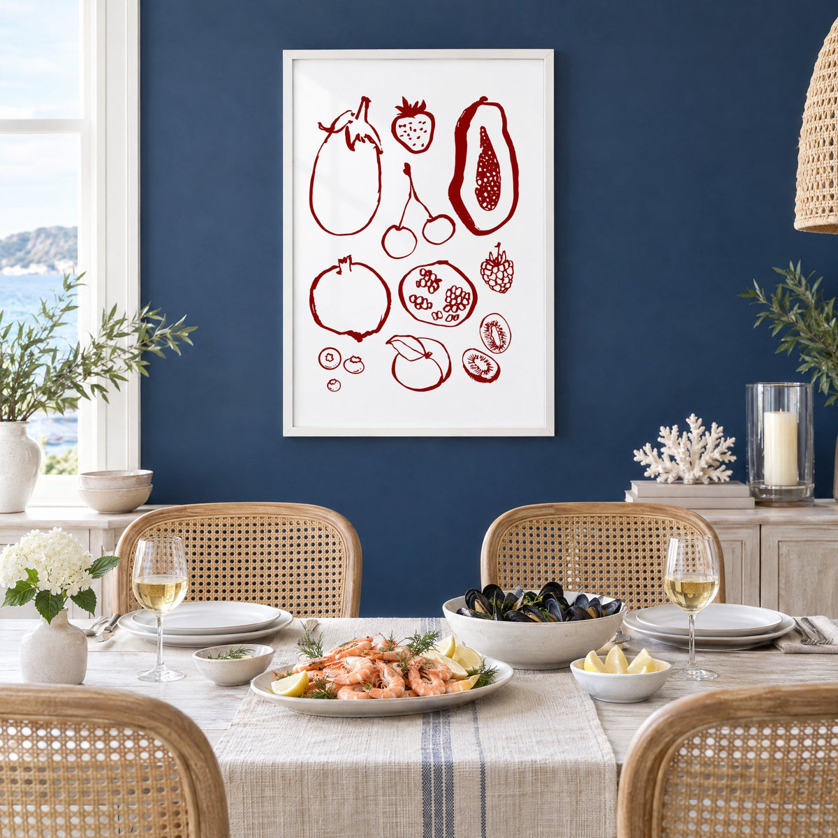 Burgundy ink fruit sketch pattern print in a white frame on a navy wall above a dining table set with shrimp and mussels