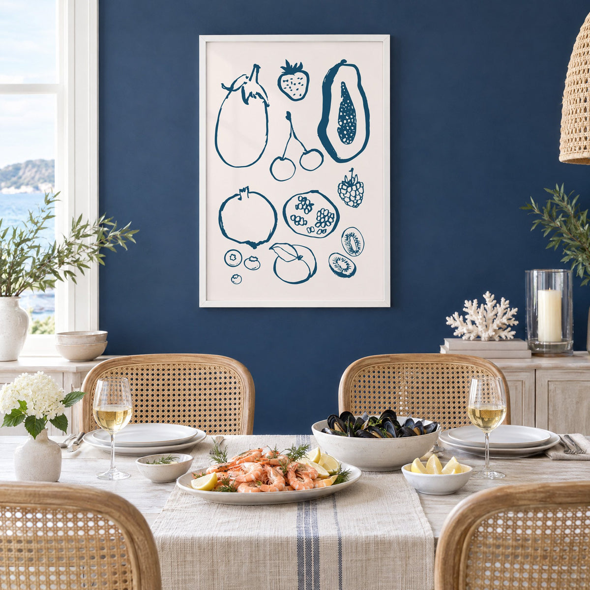 petrol blue ink fruit sketch pattern print in a white frame on a navy wall above a dining table set with shrimp and mussels