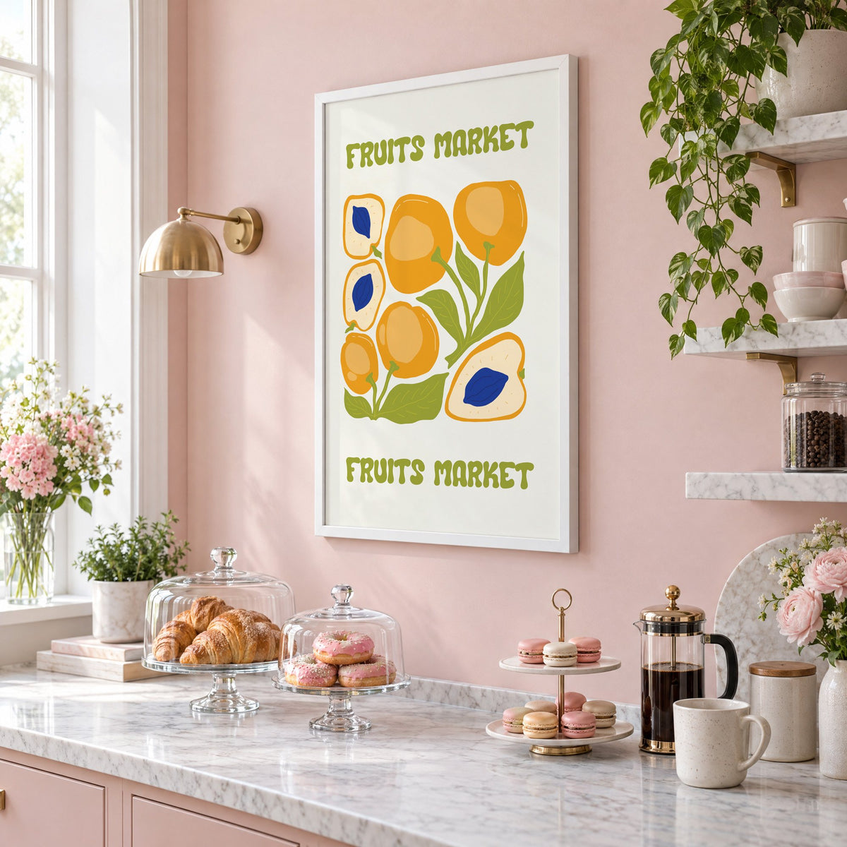 FRUITS MARKET apricots cobalt pits print in a white frame on a blush pink wall above a patisserie counter with croissants and macarons, seen at an angle