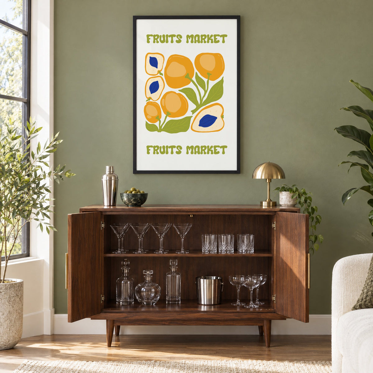 FRUITS MARKET apricots cobalt pits print in a black frame on an olive green wall above a walnut bar cabinet with glassware
