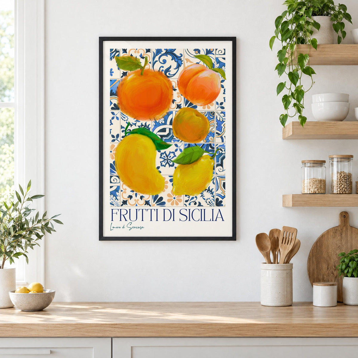 Frutti di Sicilia blue tile fruit print in a black frame in a white kitchen beside open wood shelves and glass jars