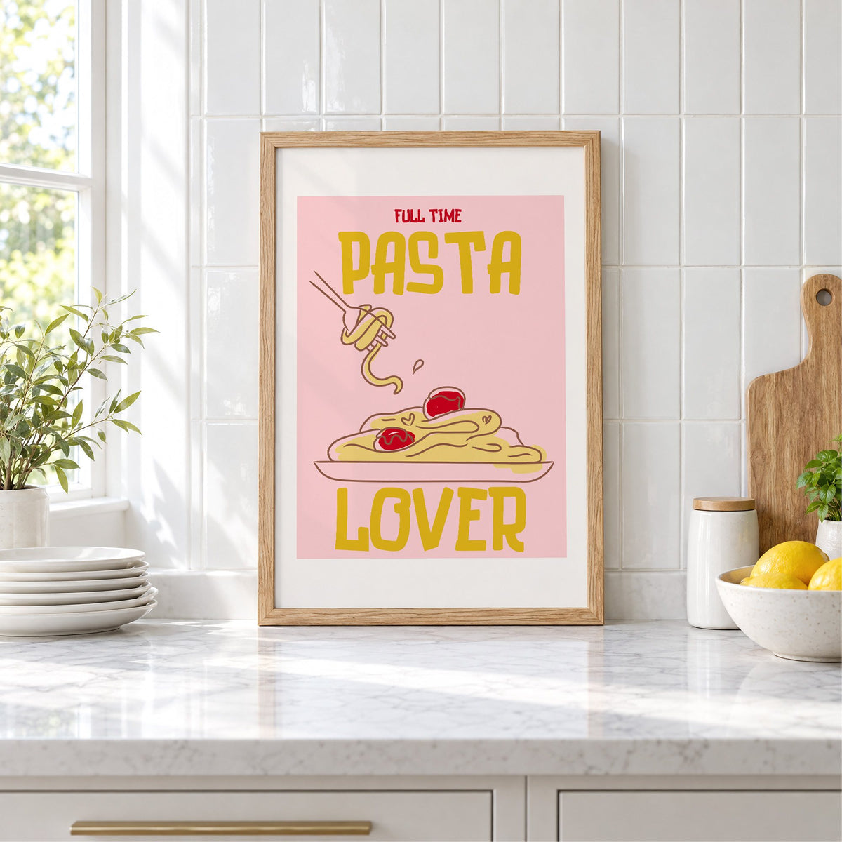 Full Time Pasta Lover spaghetti print in an oak frame leaning on a marble counter by white tiles and lemons