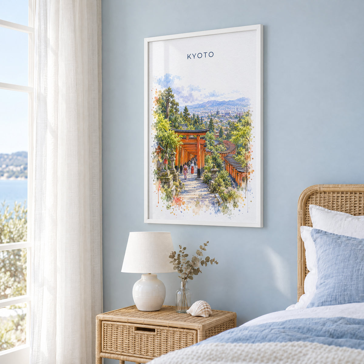 Fushimi Inari Shrine watercolor print in a white frame on a pale blue wall beside a rattan bed in a coastal bedroom