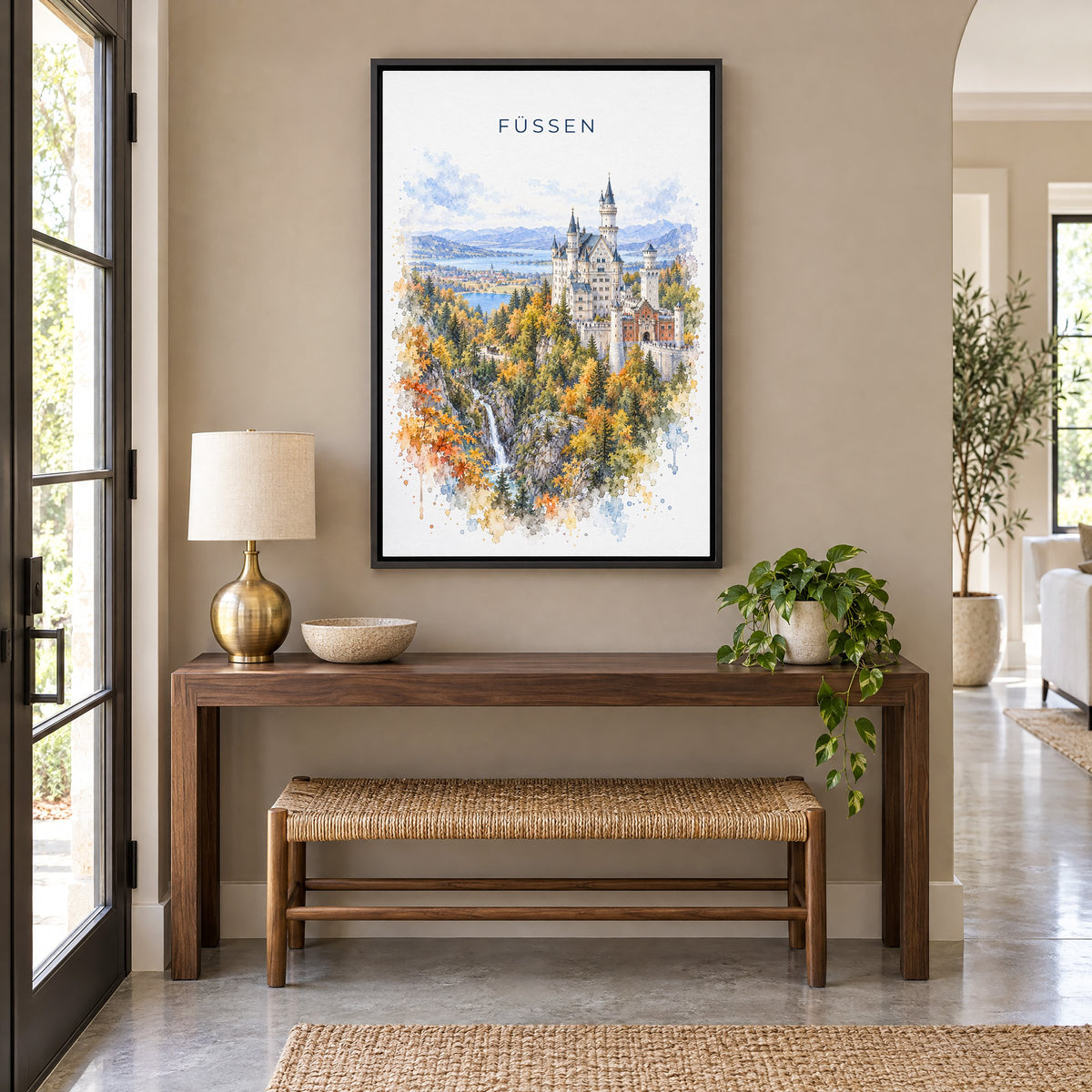 Füssen watercolor print as a black floater canvas above a walnut console and woven bench in an entryway