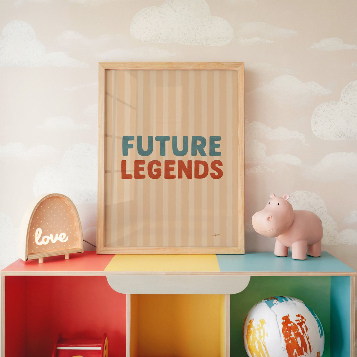Future legends retro lettering nursery print in an oak frame on a rainbow toy shelf against cloud wallpaper
