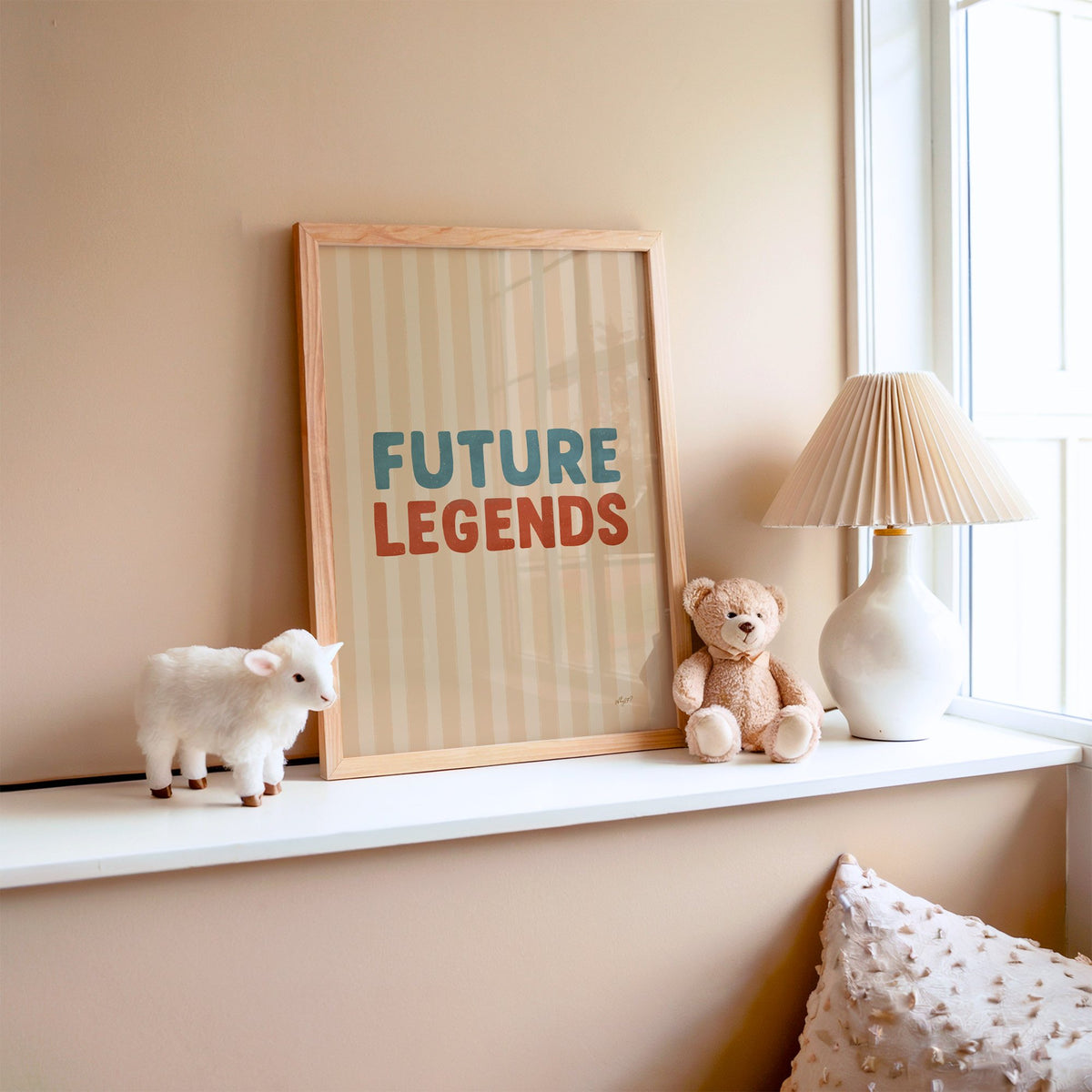 Future legends retro lettering nursery print in an oak frame on a window ledge with a toy lamb and teddy