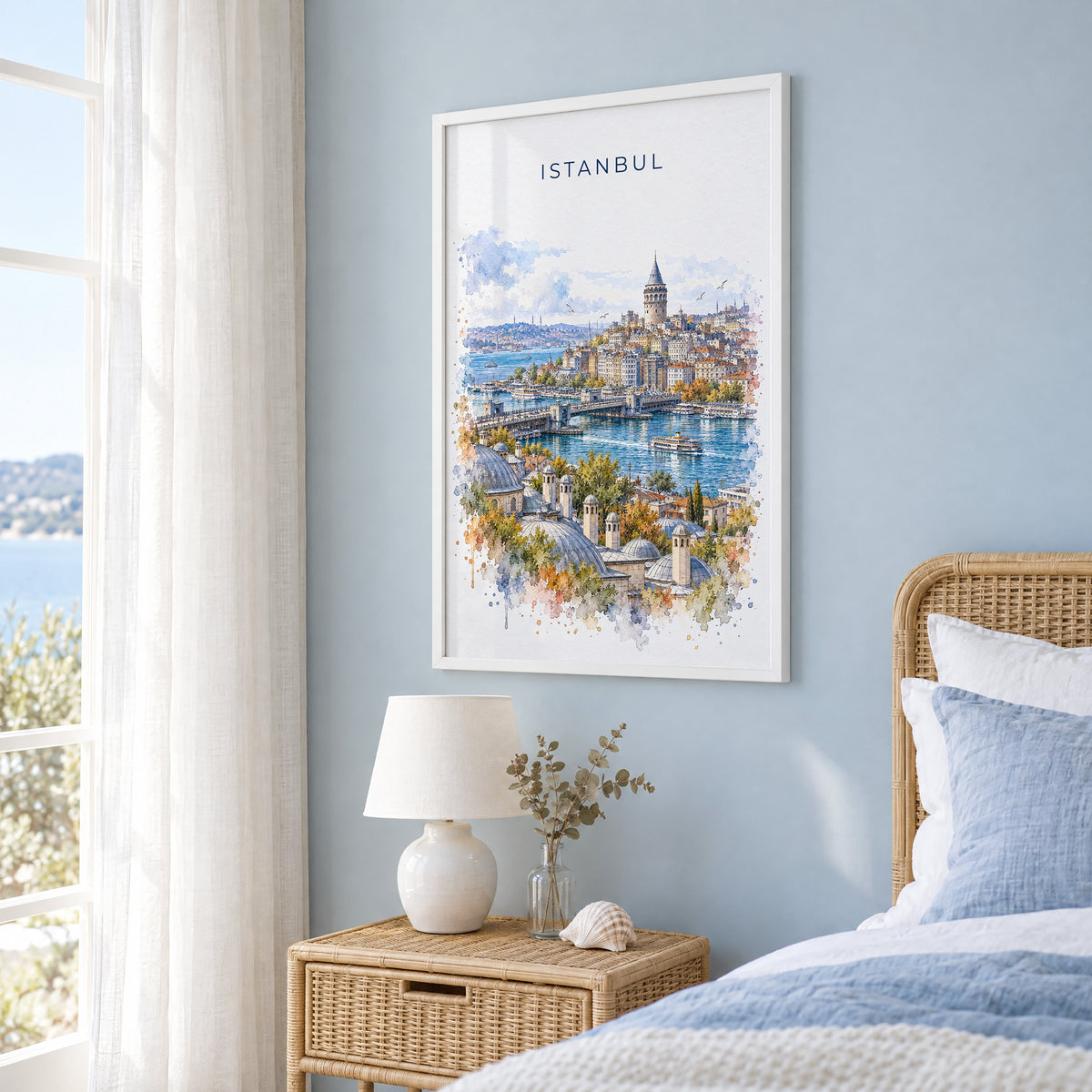 Galata Tower watercolor print in a white frame on a pale blue wall beside a rattan bed in a coastal bedroom