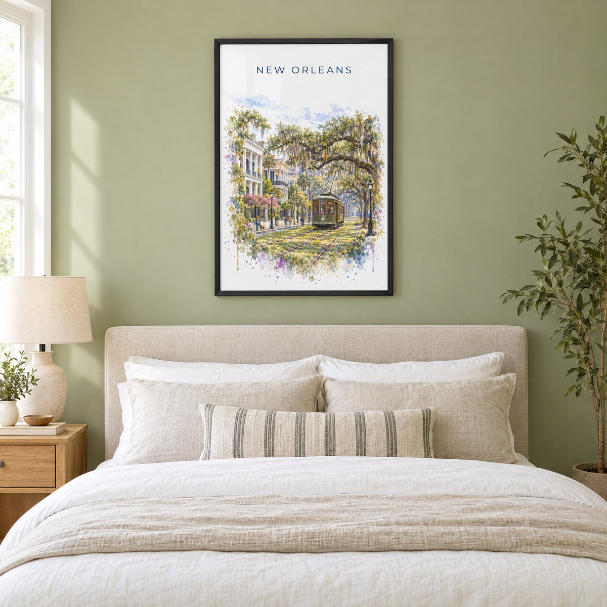 Garden District New Orleans watercolor print in a black frame above an upholstered headboard in a sage green bedroom