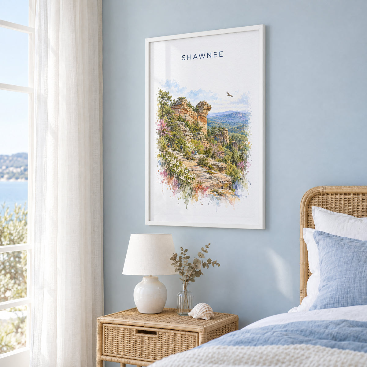 Garden of the Gods, Illinois watercolor print in a white frame on a pale blue wall beside a rattan bed in a coastal bedroom