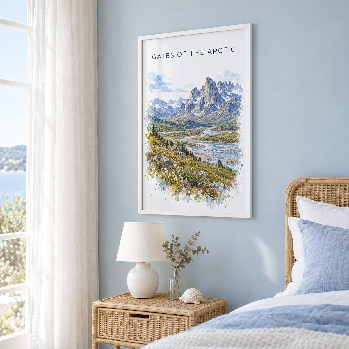 Gates of the Arctic National Park watercolor in a white frame on a pale blue wall beside a rattan bed in a coastal bedroom