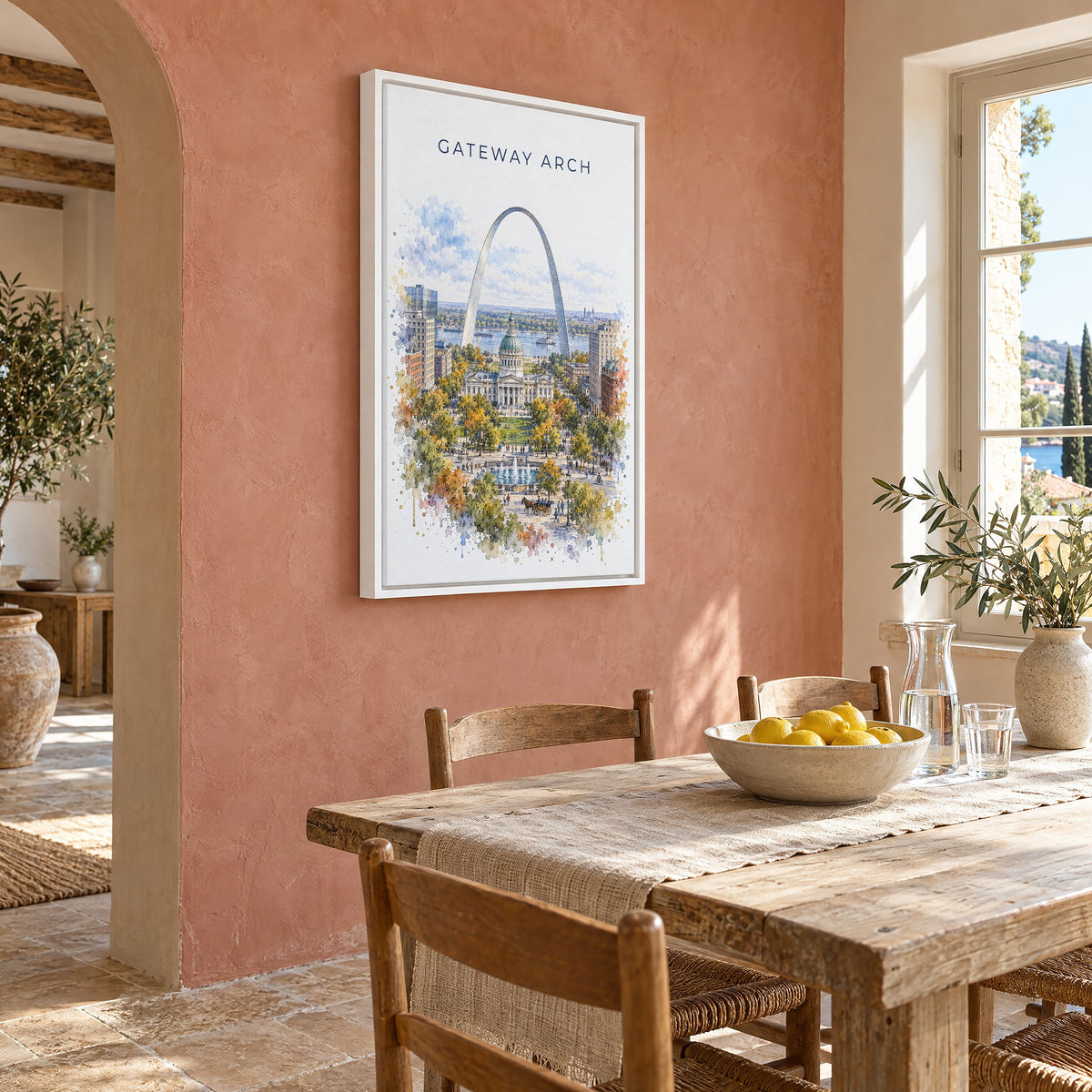 Gateway Arch National Park watercolor print as a white floater canvas on a terracotta wall above a rustic dining table