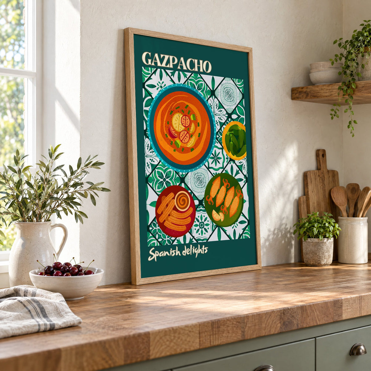 Gazpacho tapas print with teal border in an oak frame leaning on a butcher block island beside a bowl of cherries