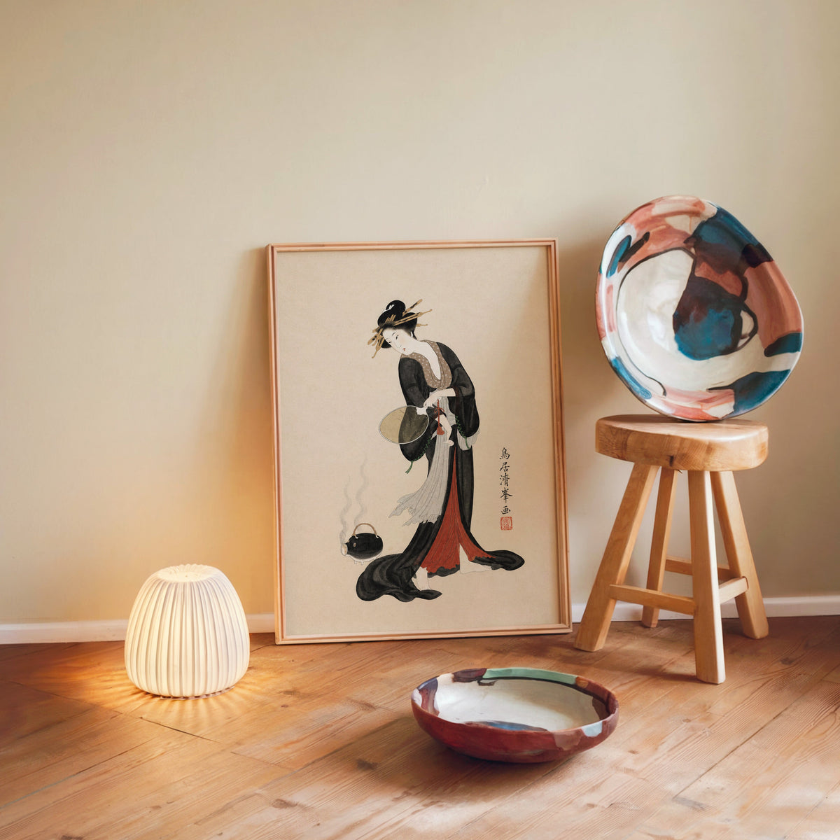 woman in black kimono with fan print in a light wood frame leaning on a wooden floor by a glowing lamp and stool