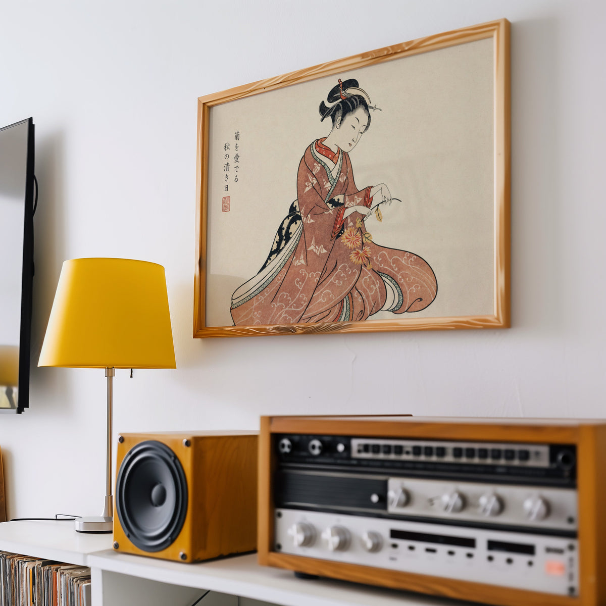 Kimono woman holding chrysanthemums print in a pine frame above a vintage stereo and a yellow table lamp