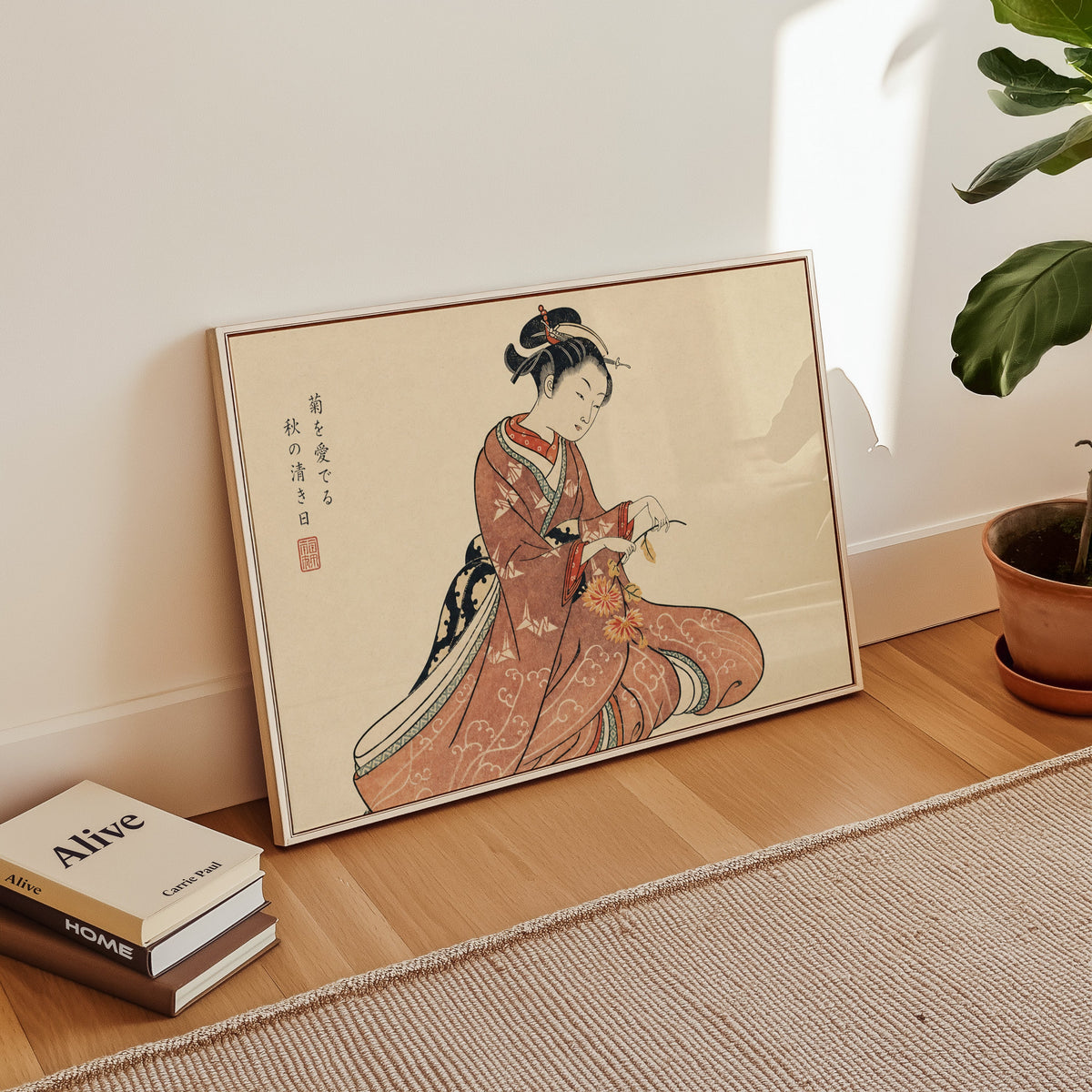 Kimono woman holding chrysanthemums print in a white floater frame leaning on a wood floor beside stacked books