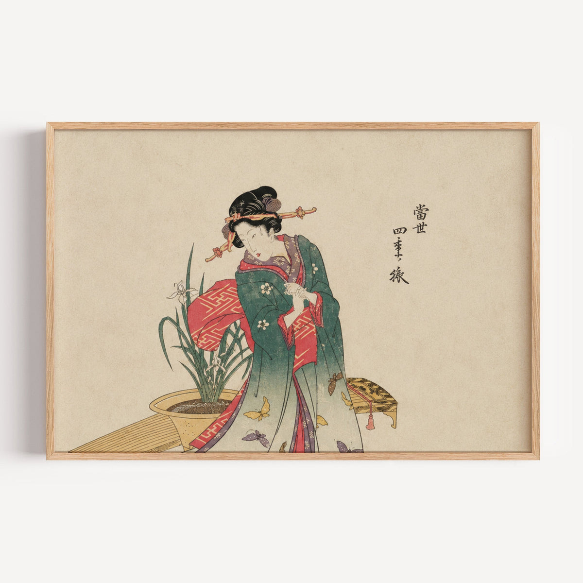 Woman in green kimono with butterflies print in a light oak frame on a plain white wall