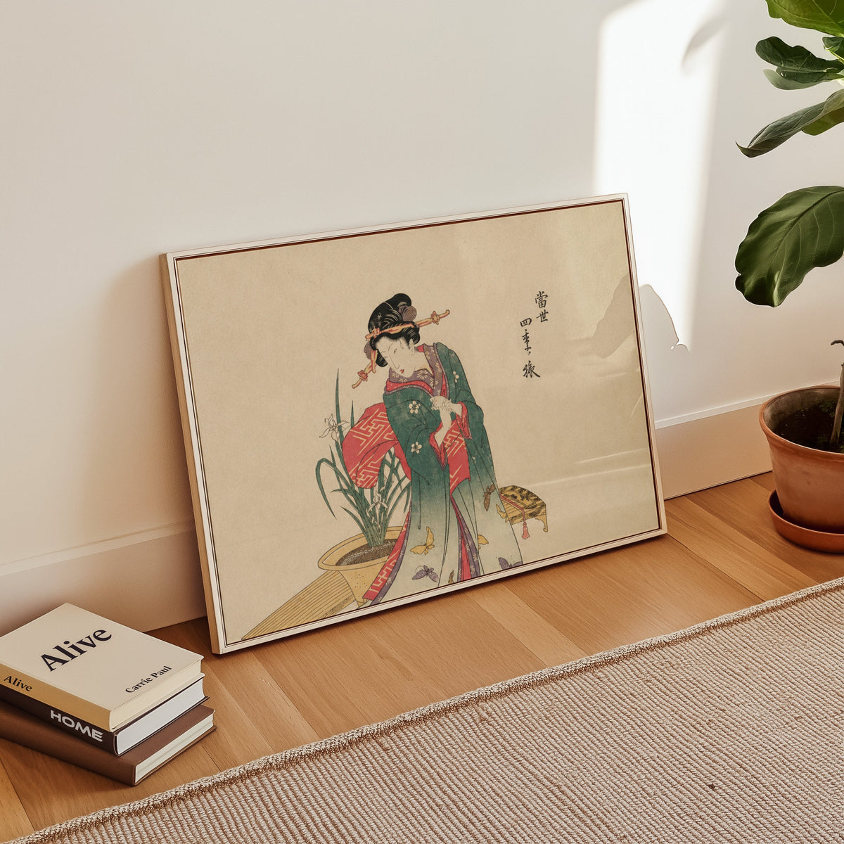 Woman in green kimono with butterflies print in a white floater frame leaning on a wood floor beside stacked books