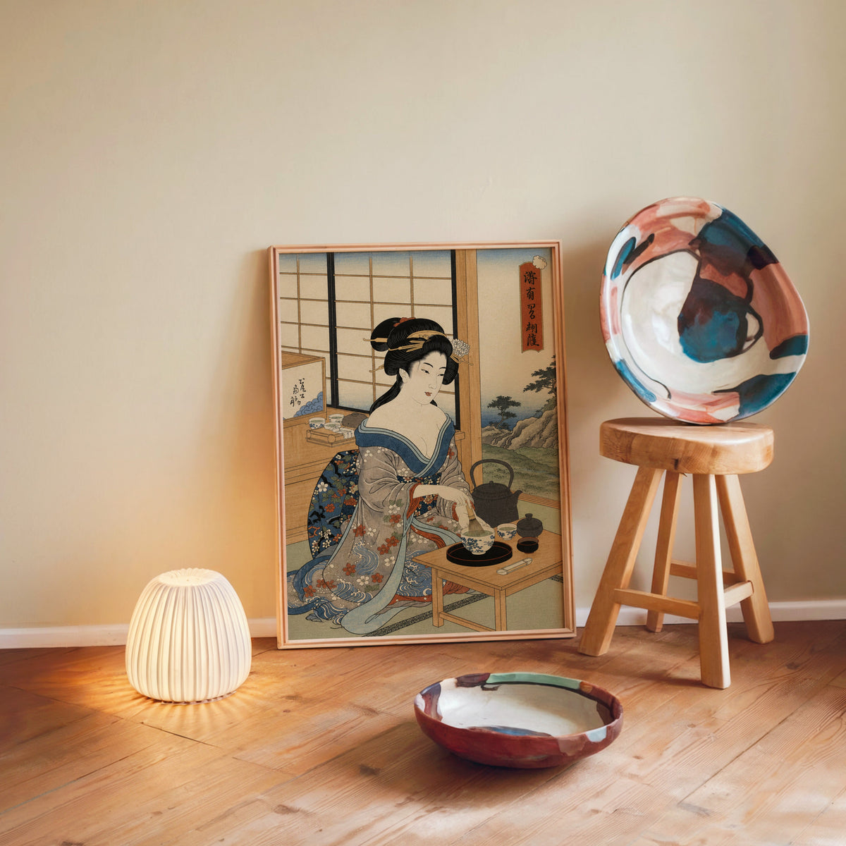 woman whisking matcha tea print in a light wood frame leaning on a wooden floor by a glowing lamp and stool