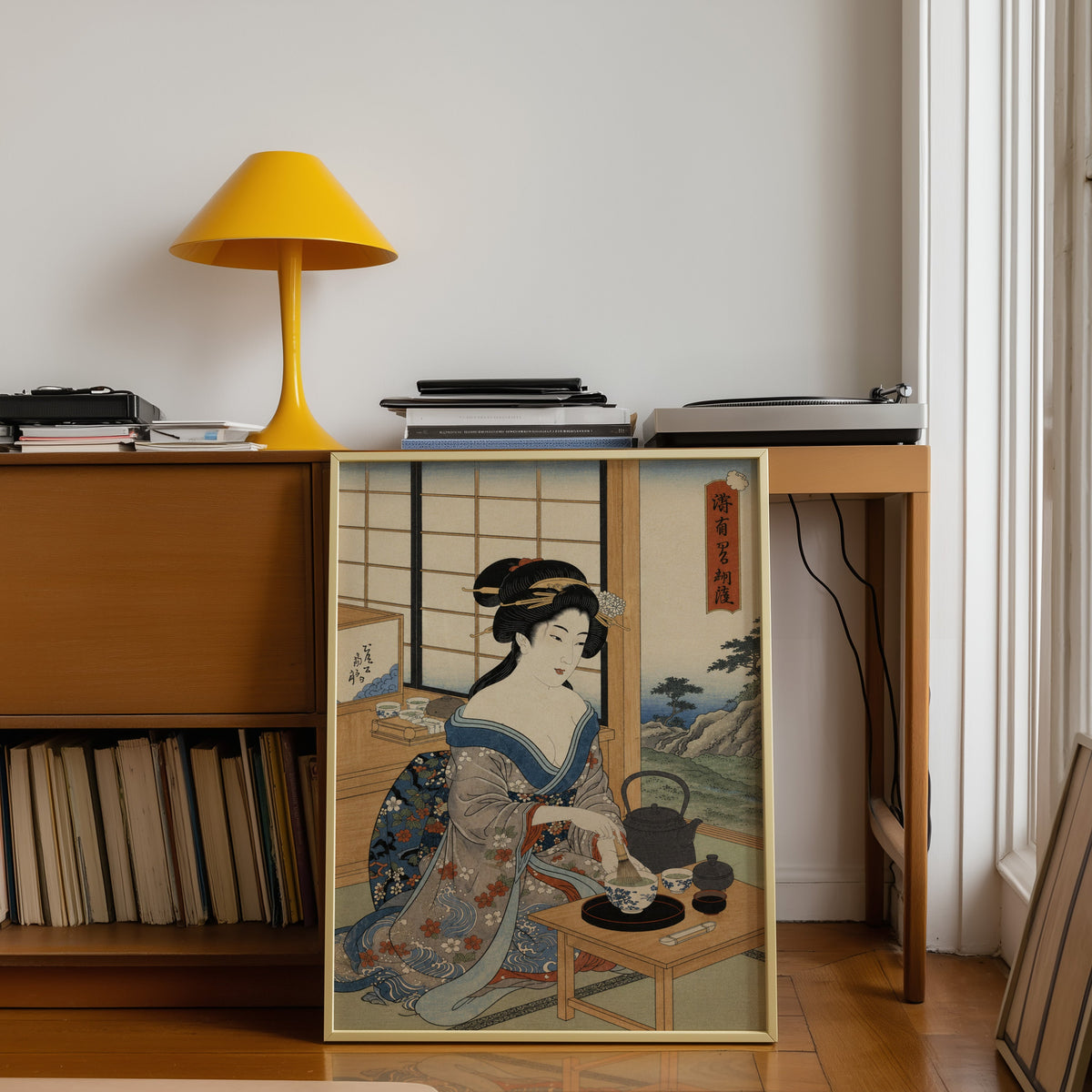 woman whisking matcha tea print shown in a gold frame leaning under a teak desk with a yellow lamp