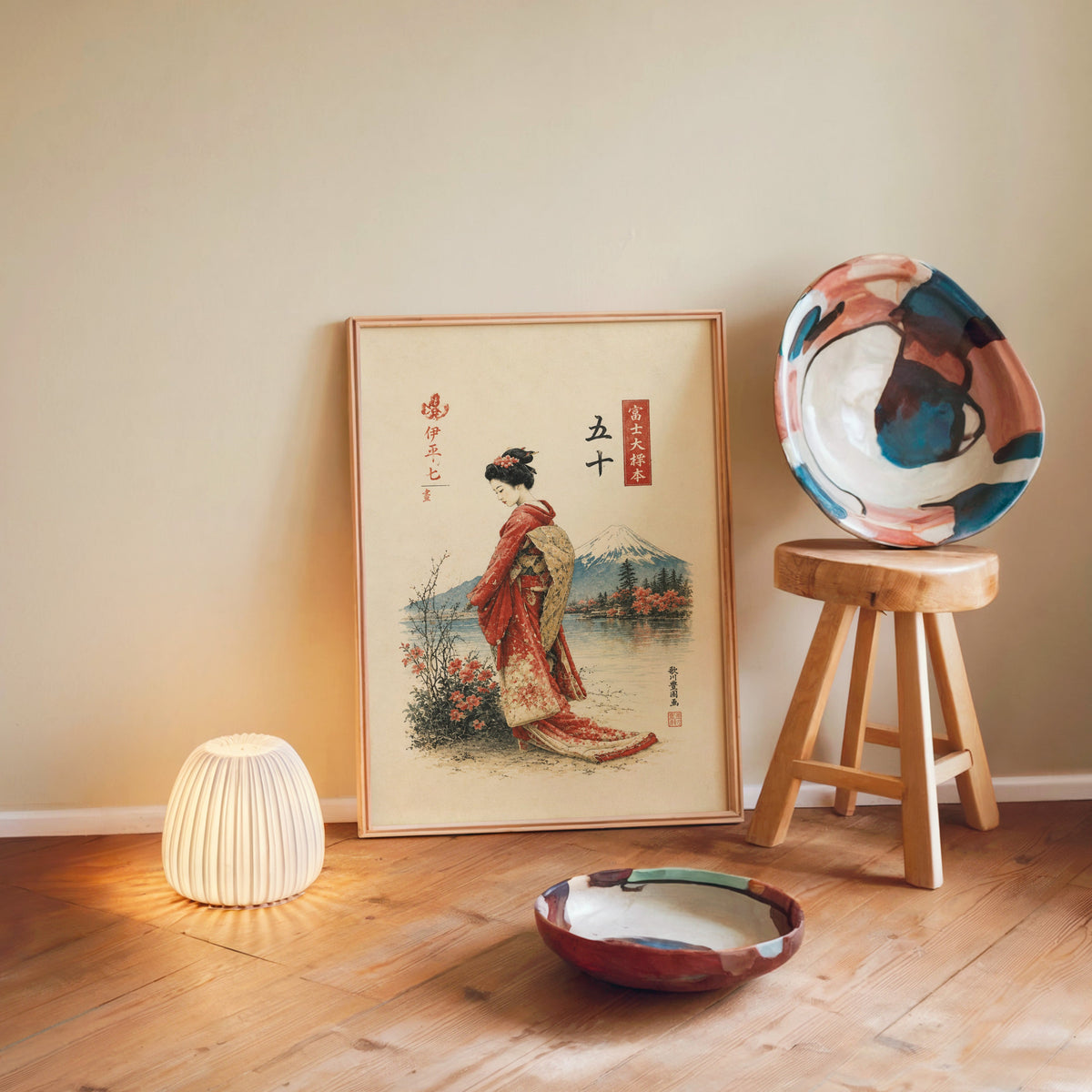 woman in red kimono by Mount Fuji print in a light wood frame leaning on a wooden floor by a glowing lamp and stool