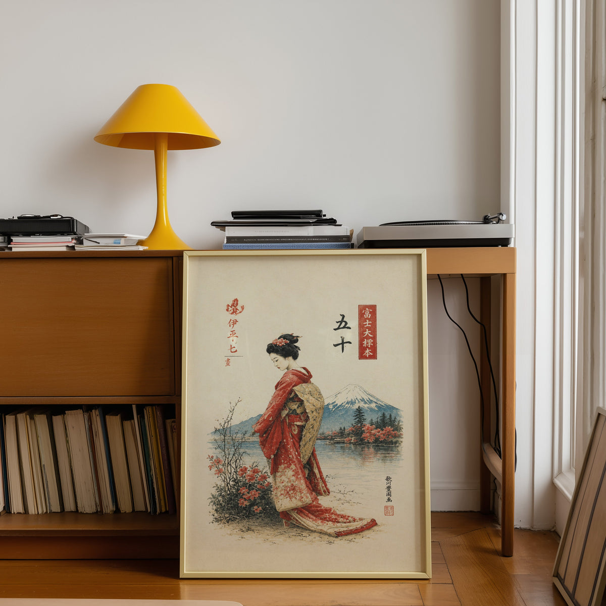 woman in red kimono by Mount Fuji print shown in a gold frame leaning under a teak desk with a yellow lamp