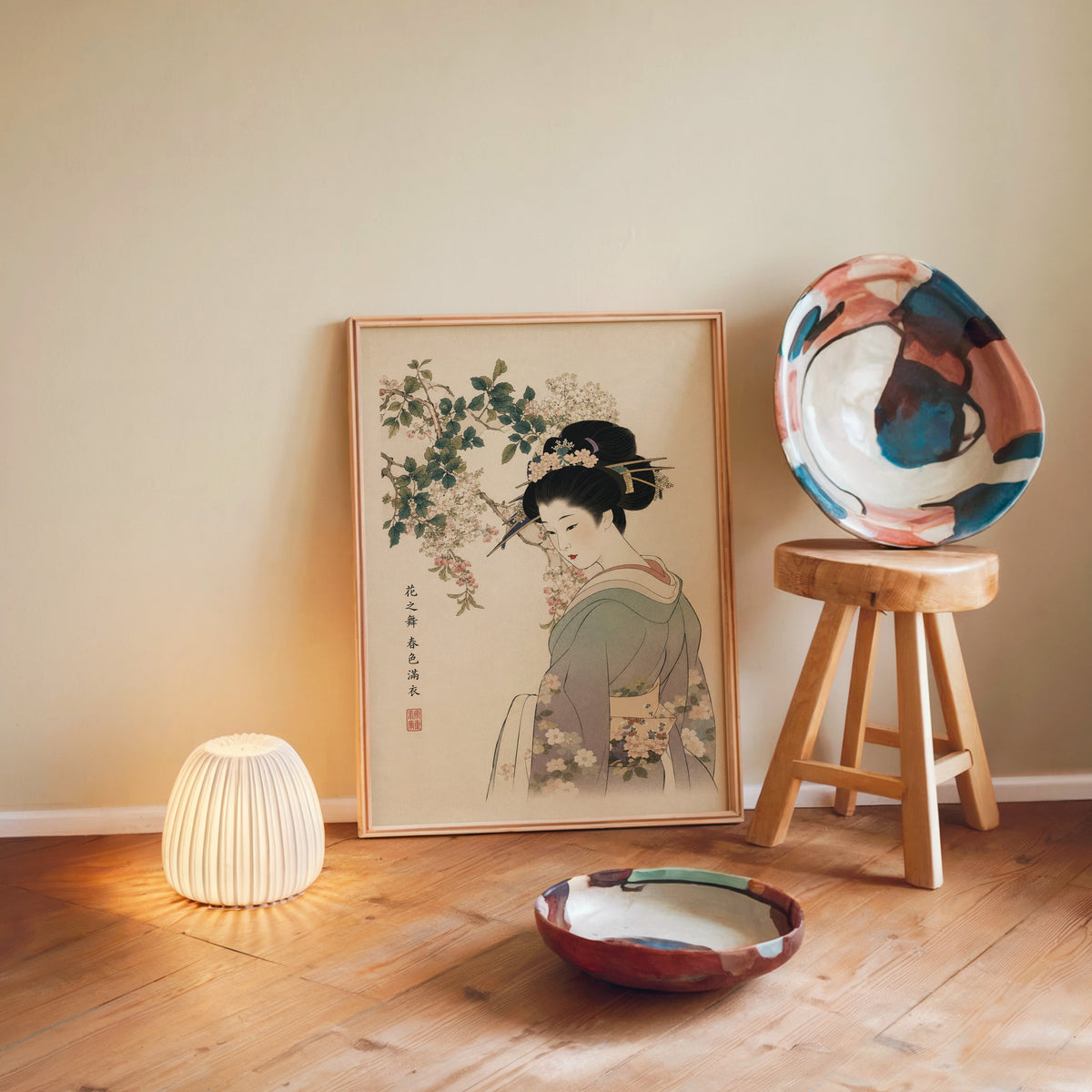 woman in lilac kimono under blossoms print in a light wood frame leaning on a wooden floor by a glowing lamp and stool