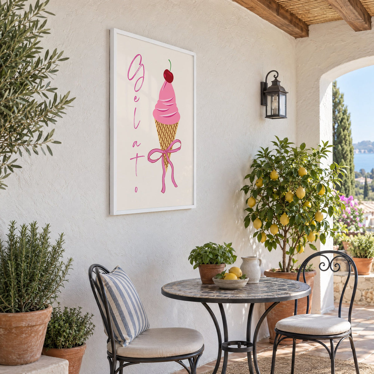Gelato pink cone with bow print in a white frame on a sunny patio wall beside a potted lemon tree