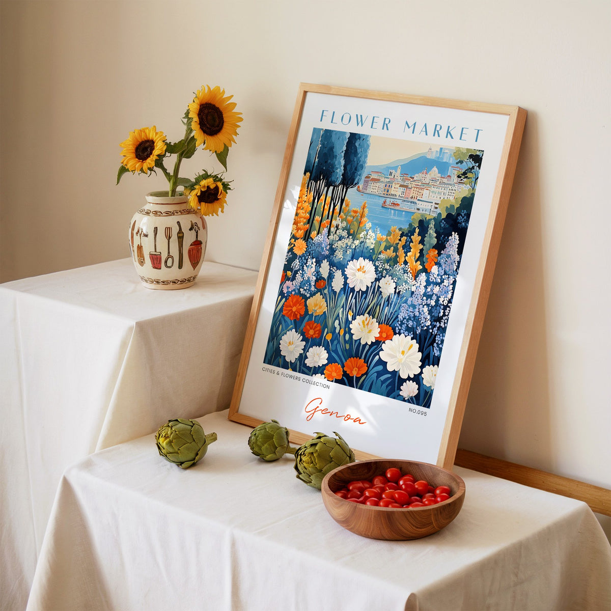 Genoa flower market print in an oak frame leaning on a linen-draped table beside a vase of sunflowers