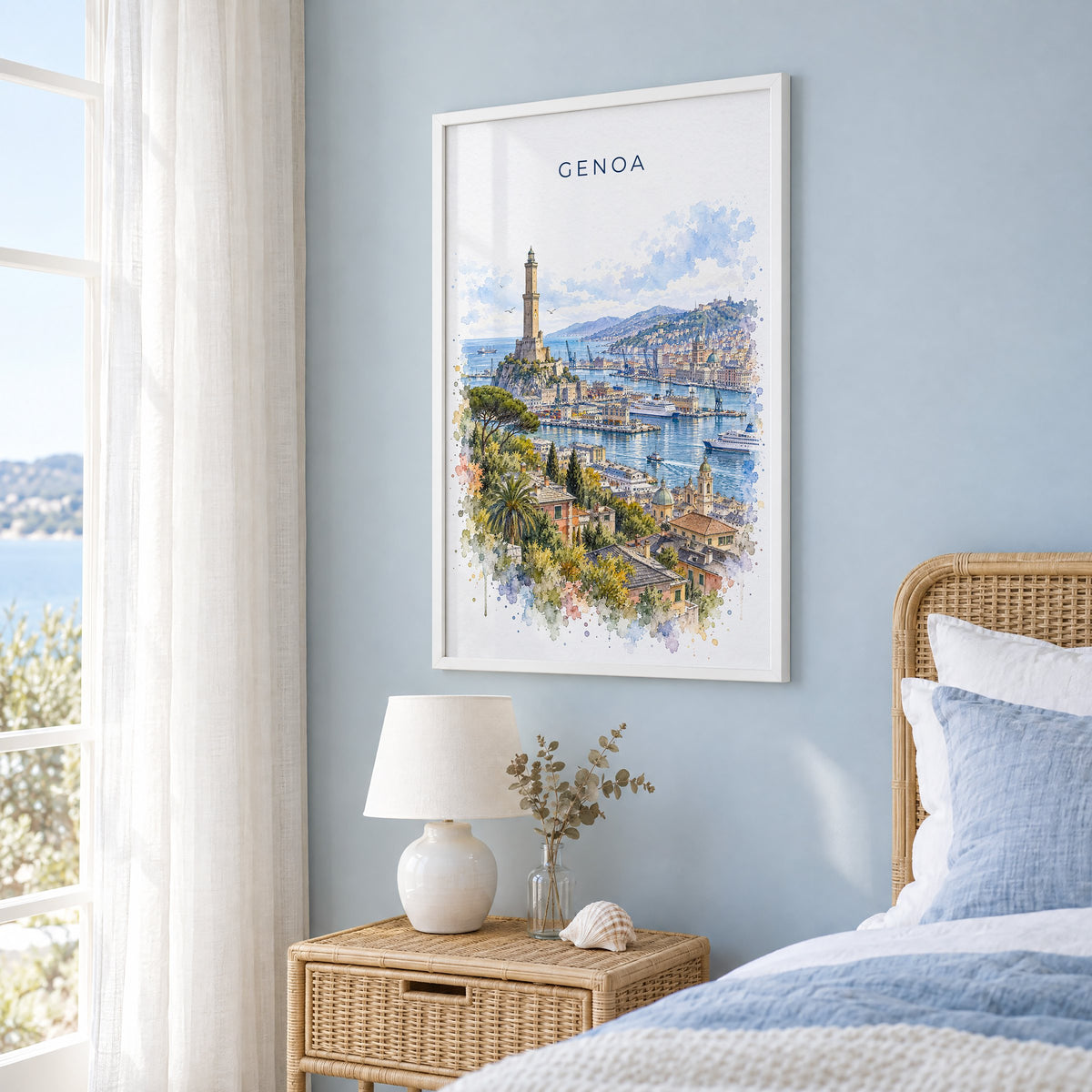 Genoa watercolor print in a white frame on a pale blue wall beside a rattan bed in a coastal bedroom