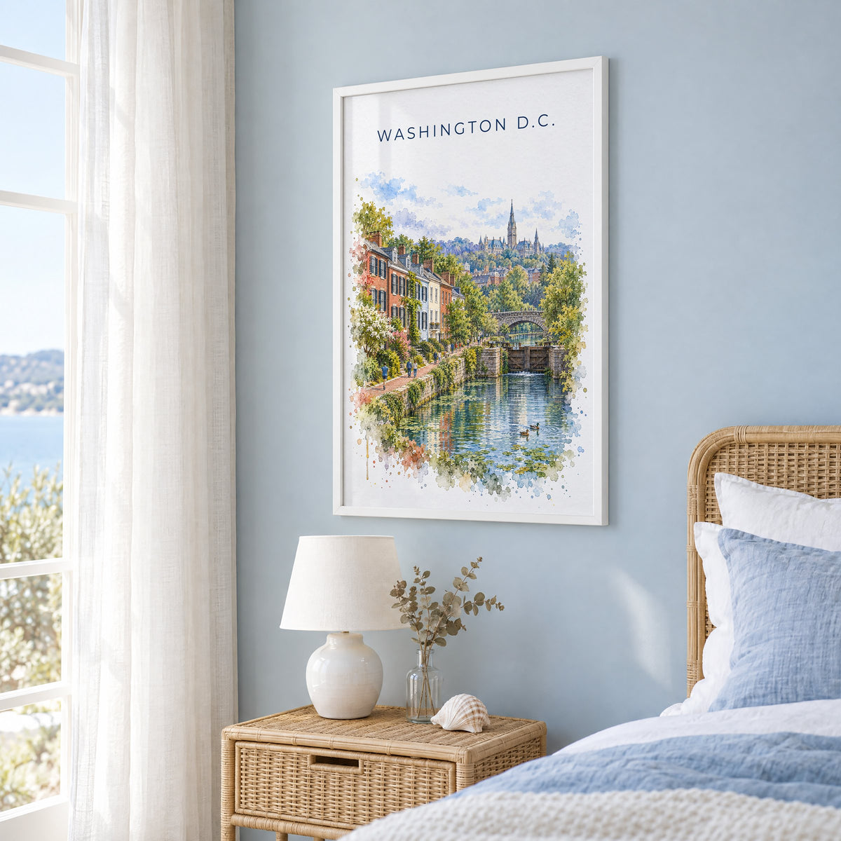 Georgetown DC watercolor print in a white frame on a pale blue wall beside a rattan bed in a coastal bedroom