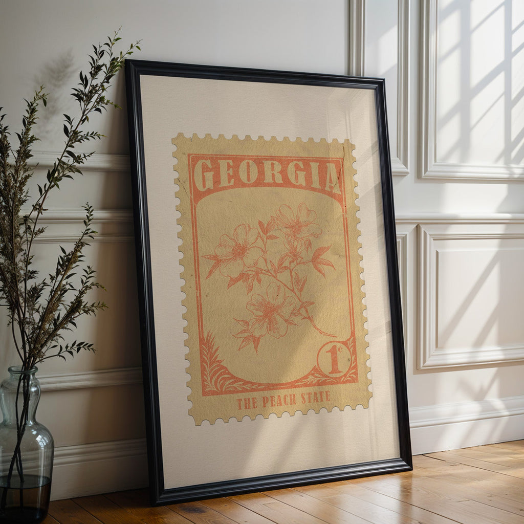 Georgia state flower print in a black frame leaning against a white panelled wall beside olive branches