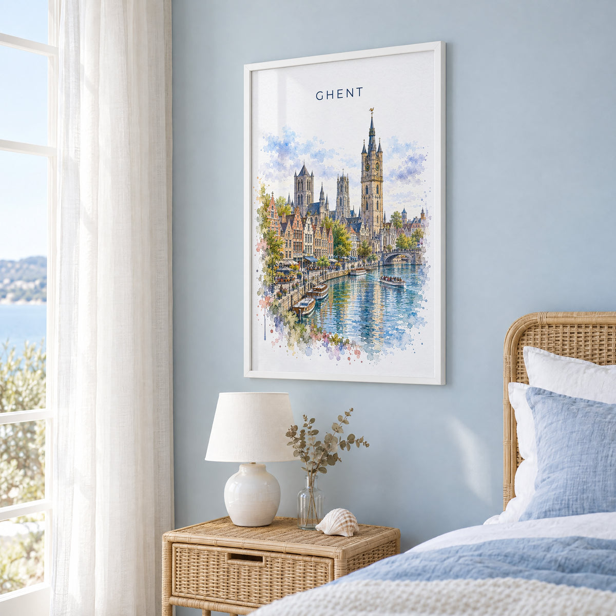 Ghent watercolor print in a white frame on a pale blue wall beside a rattan bed in a coastal bedroom
