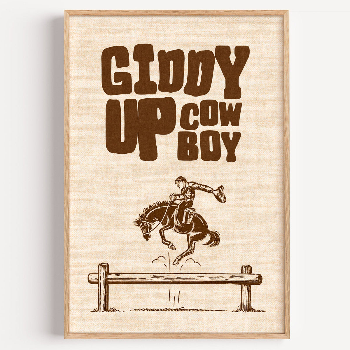Giddy Up Cowboy print in cream in a light oak frame on a plain white wall