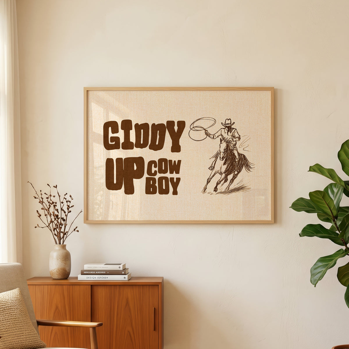 Giddy up cowboy lasso print in an oak frame above a teak sideboard with a fig plant