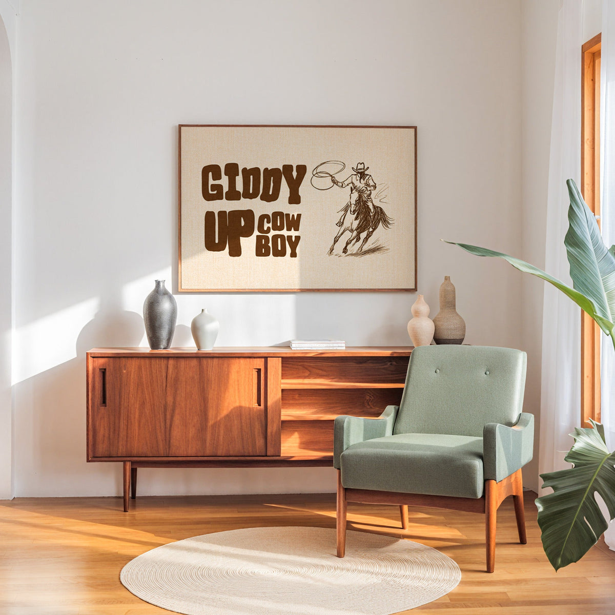 Giddy up cowboy lasso print in a walnut frame above a sideboard beside a sage armchair