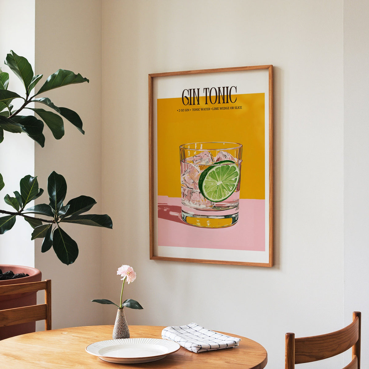Gin and tonic recipe print in a walnut frame above a round table beside a fiddle-leaf fig