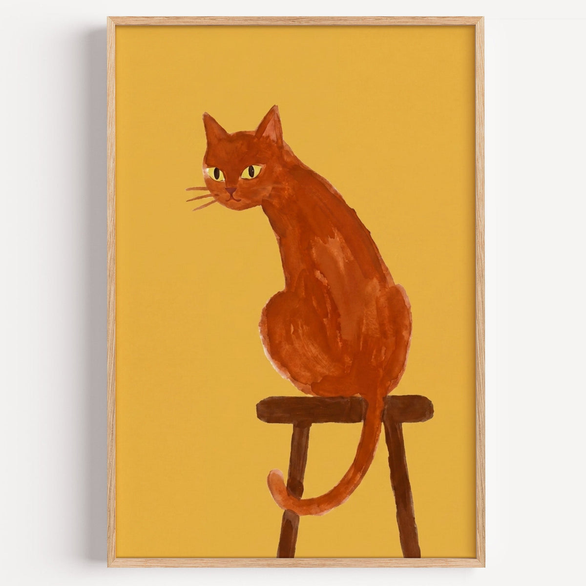 Ginger cat on wooden stool print in a light oak frame on a plain white wall