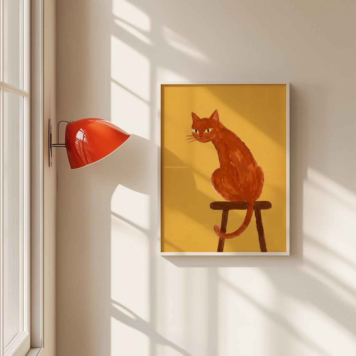 Ginger cat on wooden stool print in a white frame beside a red wall sconce