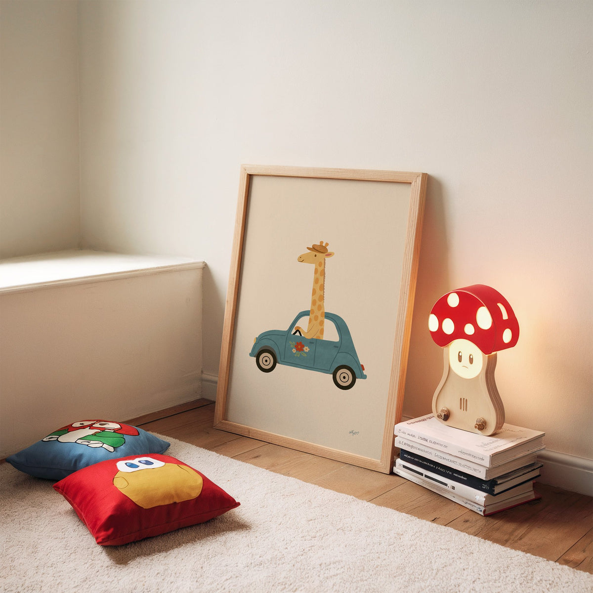 Giraffe driving a teal car nursery print in an oak frame leaning on a rug beside a mushroom lamp and floor cushions