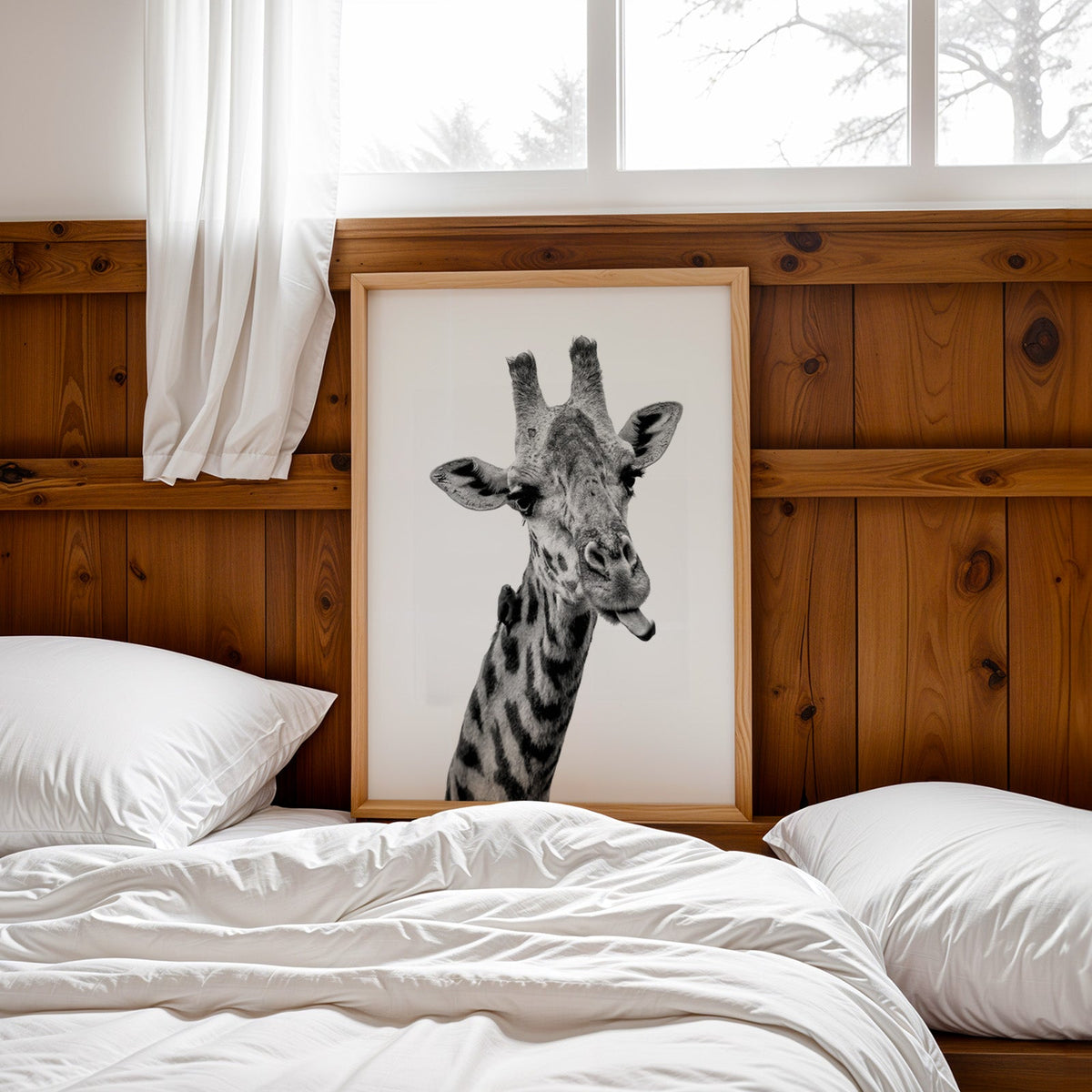 Giraffe sticking out tongue with small bird print in a pine frame leaning on a wood headboard over white bedding