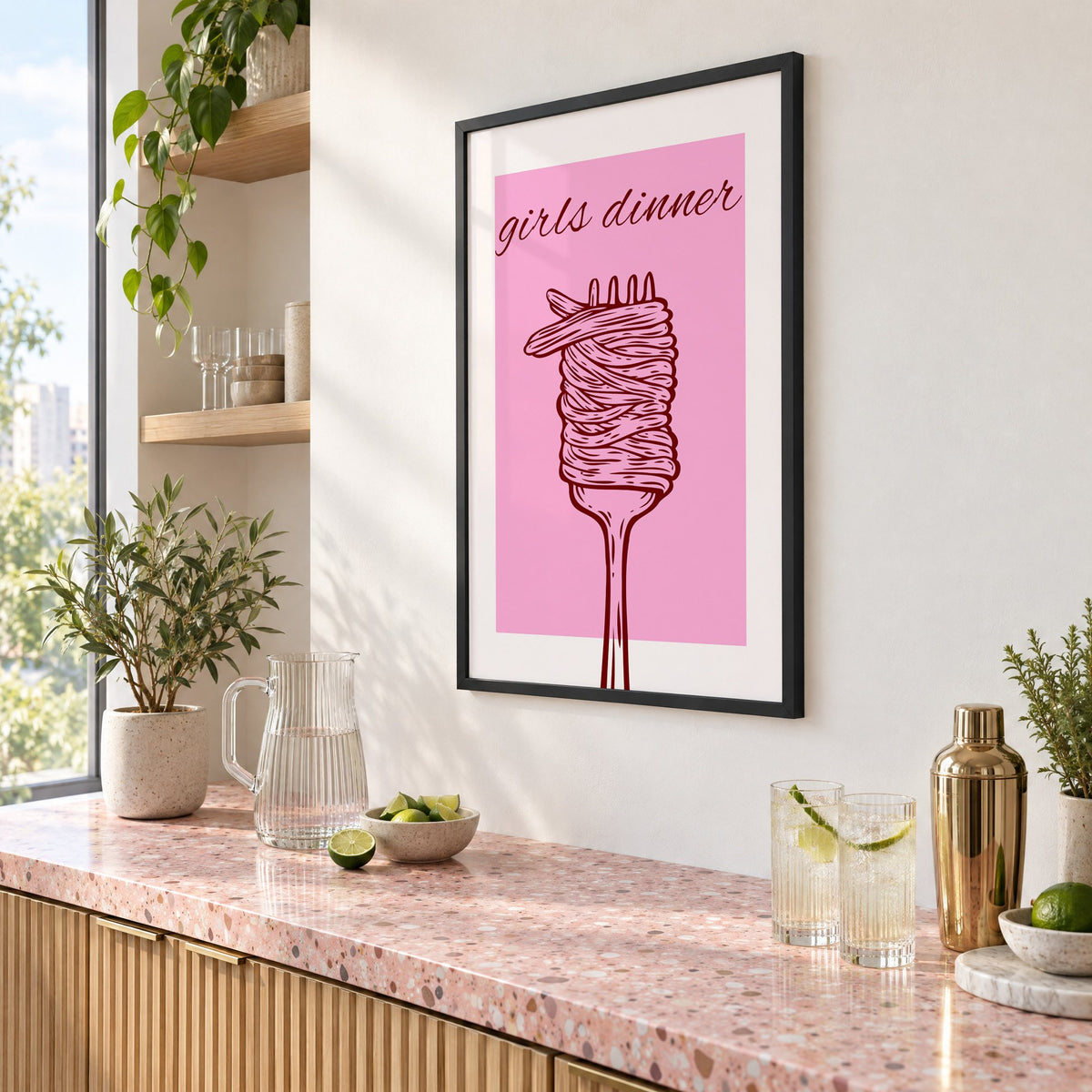 Girls dinner spaghetti fork pink print in a black frame above a pink terrazzo cocktail counter with limes, seen at an angle