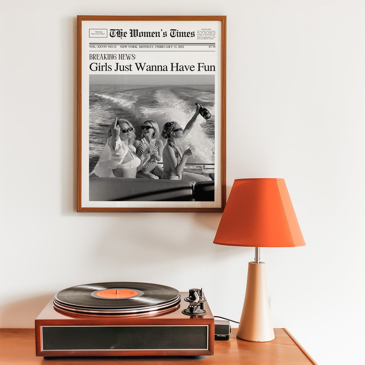 Mock front page with three women on a yacht print in a walnut frame above a record player and orange lamp